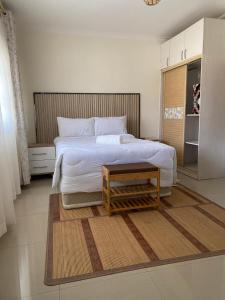 a bedroom with a large white bed and a table at Lelesha Lodge Makeni in Lusaka