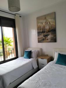 a bedroom with two beds and a painting of a sailboat at Pavillon Luxe - Jardin de l'Atlas - Golf & Waky in Sraghna