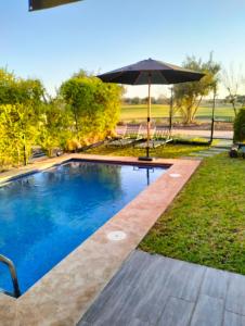 a swimming pool with an umbrella in a yard at Pavillon Luxe - Jardin de l'Atlas - Golf & Waky in Sraghna