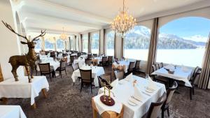 a restaurant with white tables and chairs and a large window at Hotel Waldhaus am See in St. Moritz
