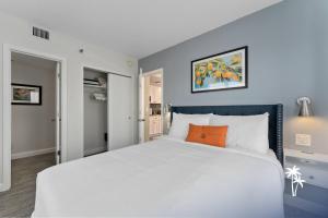 a bedroom with a large white bed with an orange pillow at Lake View Top Floor 2 Bed 2 Bath Condo with Balcony in Orlando