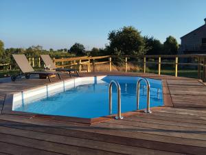 a swimming pool on a wooden deck with a bench next to it at Les Prés Grand Lodge in Montigné-le-Brillant +6 photos