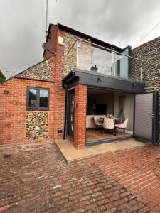 a brick house with a glass extension with a table at Small and Snug The Old Store in Broadstairs