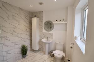a white bathroom with a toilet and a sink at Spacious 4-Bed Home in Bracknell in Bracknell