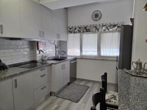 a kitchen with white cabinets and a black refrigerator at Casa da Praceta in Torres Vedras