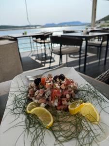 a plate of food on a table with lemon slices at Apartman Ana in Neum
