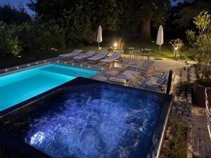 a pool with chairs and a swimming pool at night at La Meslaysienne - Comfortable house, swimming pool in Meslay-le-Vidame