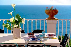 a table with a vase and flowers on a balcony at Celebrity Suite - Big Terrace on the Sea in Praiano