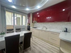 a kitchen with red cabinets and a table with chairs at Большая 2х ком in Uralsk +9 photos