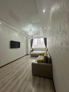a living room with a couch and a television at Большая 2х ком in Uralsk