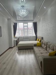 a large living room with a couch and a chandelier at Большая 2х ком in Uralsk
