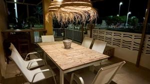 a wooden table with white chairs and a chandelier at BeachFront Apartment in Gandia in Puerto de Gandía