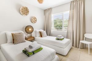 a living room with two white beds and a window at Blenchi Apartments Curacao in Willemstad +38 photos