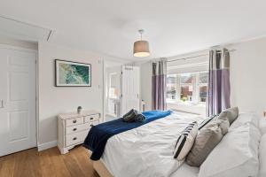 a white bedroom with a bed and a window at Polmont Haven: Spacious 4- Bedroom Retreat in Polmont