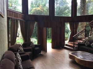 a living room with couches and a table and large windows at Cabaña del RIO by Bellavista Cabañas in Mazamitla