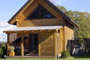 a large wooden cabin with a porch and a roof at Leniwe Chaty in Szklarnia