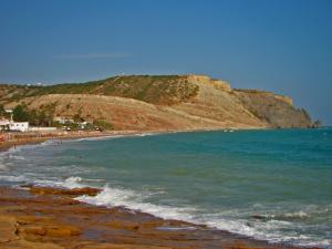 a beach with people on the water and a cliff at Vilamar in Luz