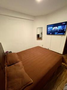 a bedroom with a bed and a tv on the wall at Moderno Depto Av América 2 habitaciones in Cochabamba +3 photos