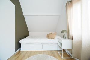 a small bedroom with a white bed and a nightstand at GITE de LA COUR DES CHASSEURS in La Wantzenau