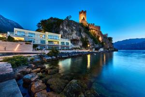 a castle on a hill next to a body of water at Hotel Castello Lake Front in Malcesine