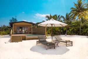 a house on the beach with two chairs and an umbrella at Nala Maldives by Jawakara in Lhaviyani Atoll