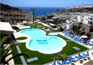 Una gran piscina con sillas y el océano. en Apartamentos Natural Park, en Puerto Rico de Gran Canaria
