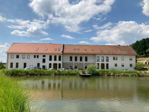 Ferienwohnungen am Büchlhof im Oberpfälzer Seenland في نينبورغ فورم والد: مبنى كبير بجانب تجمع المياه