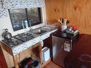 a kitchen with a sink and a stove and a window at Refugio de montaña con vista al mar in Curiñanco +27 photos