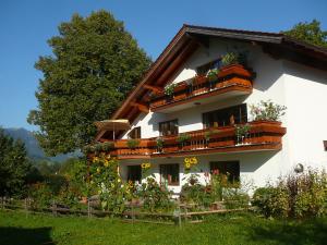 ein weißes Gebäude mit Blumenkästen an den Fenstern in der Unterkunft Landhaus Heinrich in Ruhpolding