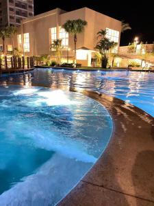 a large swimming pool with blue water at night at Aqualand Resort in Salinópolis +8 photos