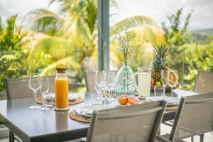 レ・トロワ・イレにあるVilla Hateya, vue mer et piscine privéeのグラスとオレンジジュースが置かれたテーブル