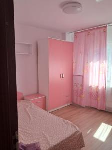 a bedroom with a pink cabinet and a bed at Adrian in Piteşti