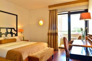 a hotel room with a bed and a desk and a window at Pousada Convento de Tavira in Tavira