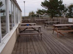 eine Reihe von Picknicktischen auf einem Deck in der Unterkunft Chalets & Lodges at Atlantic Bays Holiday Park in Padstow