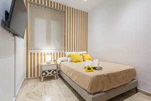 Un dormitorio con una cama con almohadas amarillas y un televisor. en Cadiz Playa 3 Rooms, en Cádiz