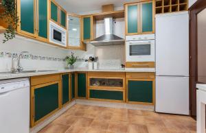 a kitchen with green cabinets and a white refrigerator at Cadiz Playa 3 Rooms in Cádiz