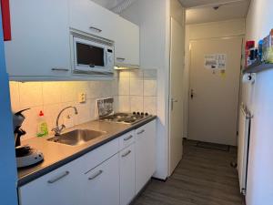 a kitchen with a sink and a microwave at Strandslag A233 in Ons Belang +3 photos