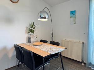 a dining room table with chairs and a lamp at Strandslag A233 in Ons Belang