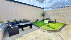 a patio with a couch and a table and grass at Maison design 11 pers -Terrasse -Netflix -Confort in Amiens
