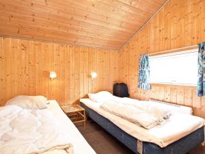 2 Betten in einem Zimmer mit Holzwänden und einem Fenster in der Unterkunft 8 person holiday home in Rødby-By Traum in Kramnitse