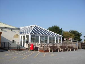 a building with a pavilion with benches in a parking lot at Chalets & Lodges at Atlantic Bays Holiday Park in Padstow