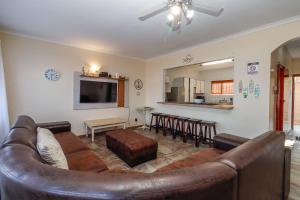 a living room with a brown leather couch and a kitchen at Carrick-A-Rede 7 in Margate
