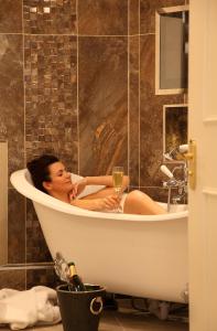 a woman sitting in a bath tub with a glass of wine at Macdonald Bath Spa Hotel in Bath