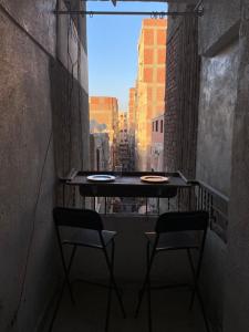 ein Tisch und zwei Stühle auf einem Balkon mit Fenster in der Unterkunft For Coffee Lovers in Kairo + 2 Fotos