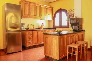 a kitchen with wooden cabinets and a stainless steel refrigerator at Charming House with Pool in Buenavista del Norte in Buenavista del Norte