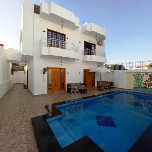 una villa con piscina frente a una casa en Christine Home, en Luxor