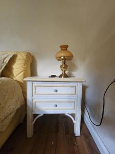 ein weißer Tisch mit einer Lampe neben einem Bett in der Unterkunft Cosy Cottage Rooms near Autobahn A2 & Hannover in Barsinghausen