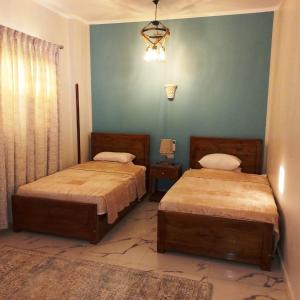 2 camas en un dormitorio con una pared verde en Christine Home, en Luxor 41 fotos más