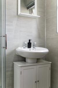a bathroom with a white sink and a mirror at Bright 3br Home In Central Belfast in Belfast