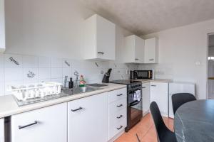 a kitchen with white cabinets and a black table at Bright 3br Home In Central Belfast in Belfast +24 photos